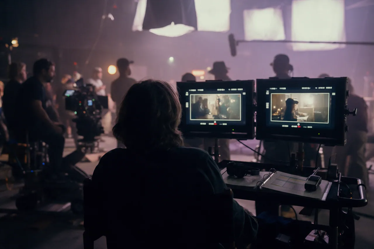Productora frente a los monitores de un set de rodaje mientras el equipo prepara la toma